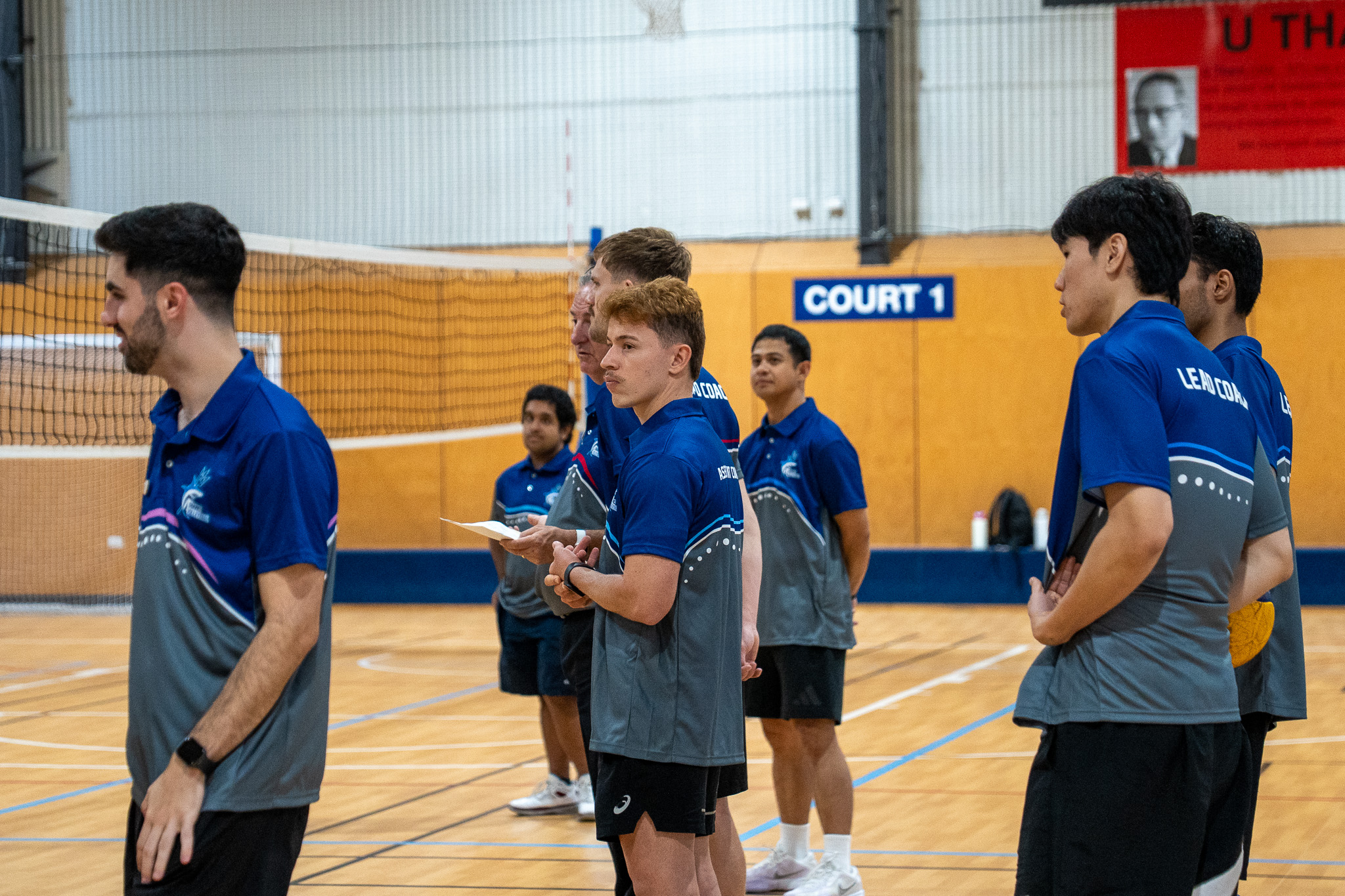 Sharks Volleyball coaches in current uniforms preparing beside the court during a 2026 session