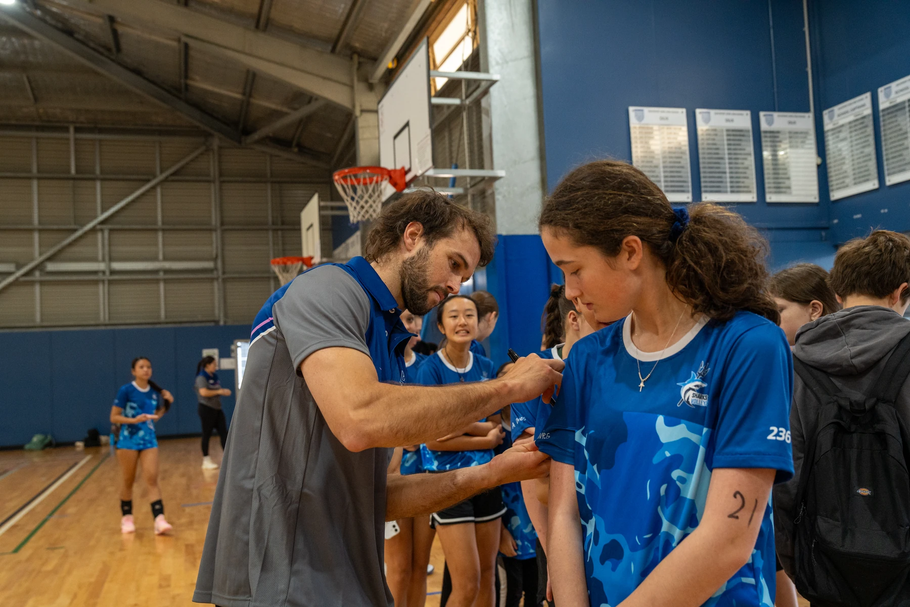 A Sharks Volleyball coach signing an athlete's shirt during a session