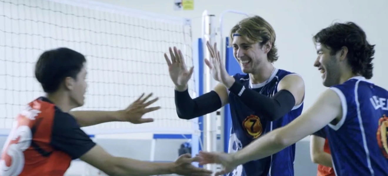 Johnny James celebrating with teammates on a volleyball court