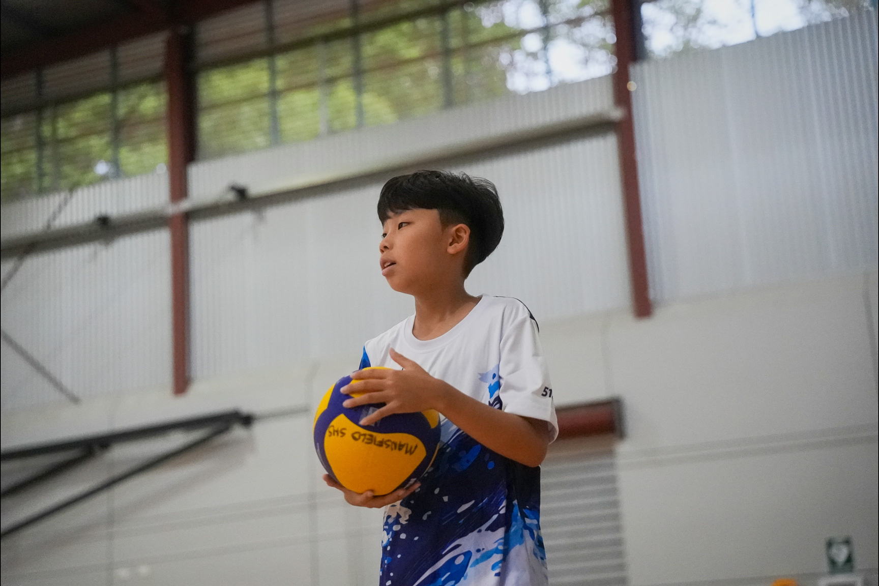 Young Sharks Volleyball athlete holding a volleyball and preparing to train