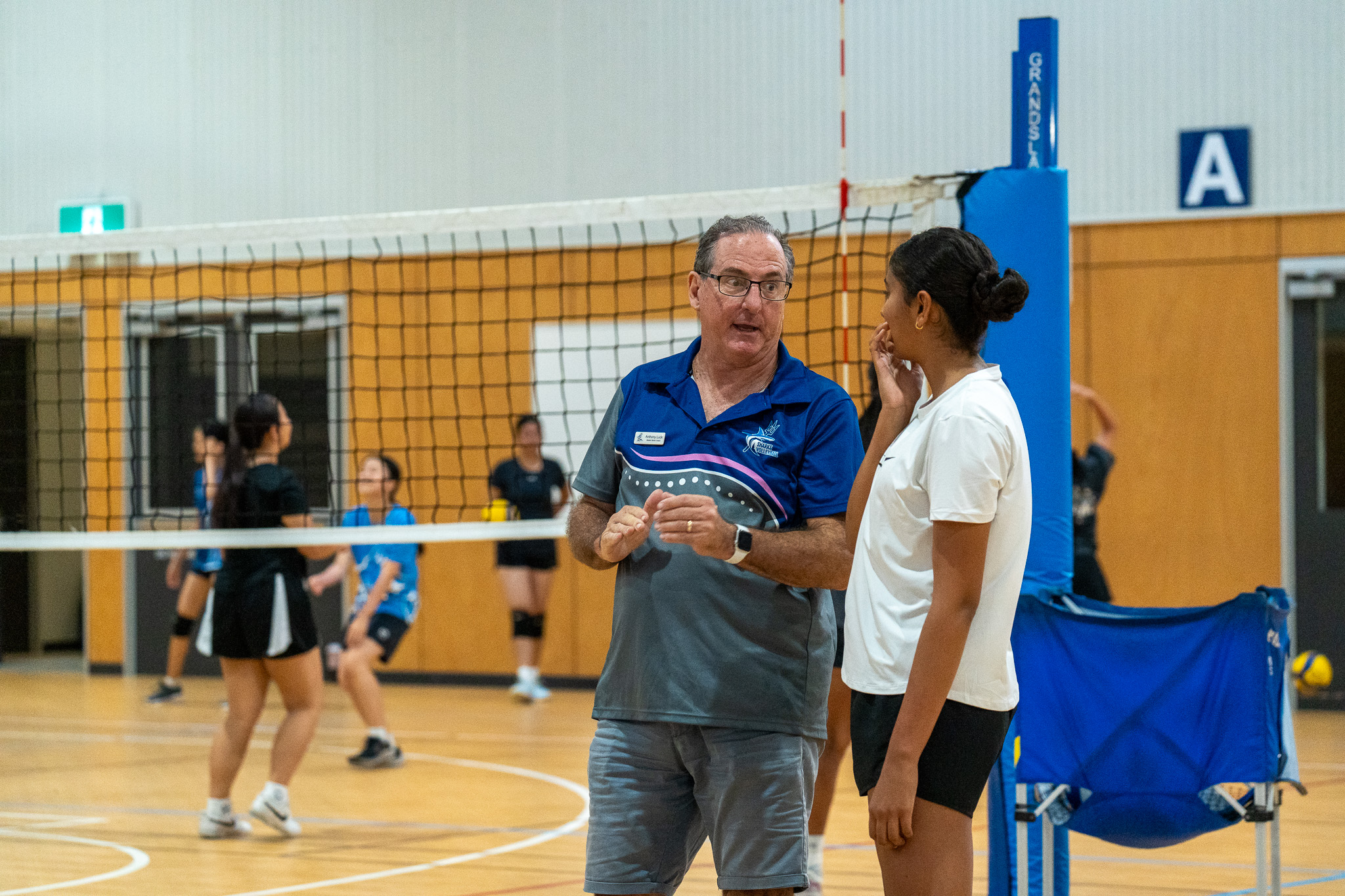 Sharks Volleyball coach giving an athlete focused technical feedback on court