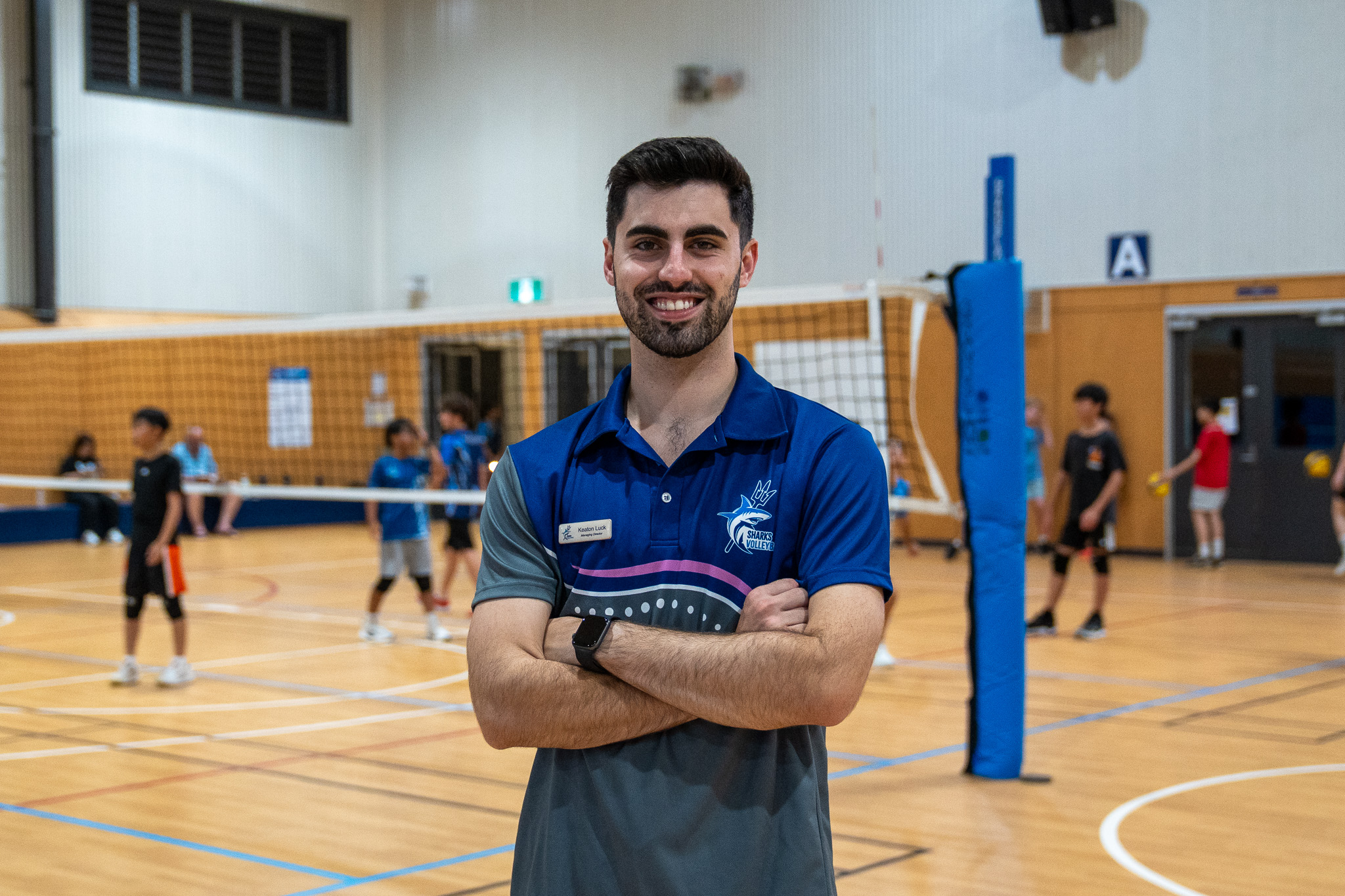 Sharks Volleyball founder Keaton Luck standing courtside in current coaching uniform