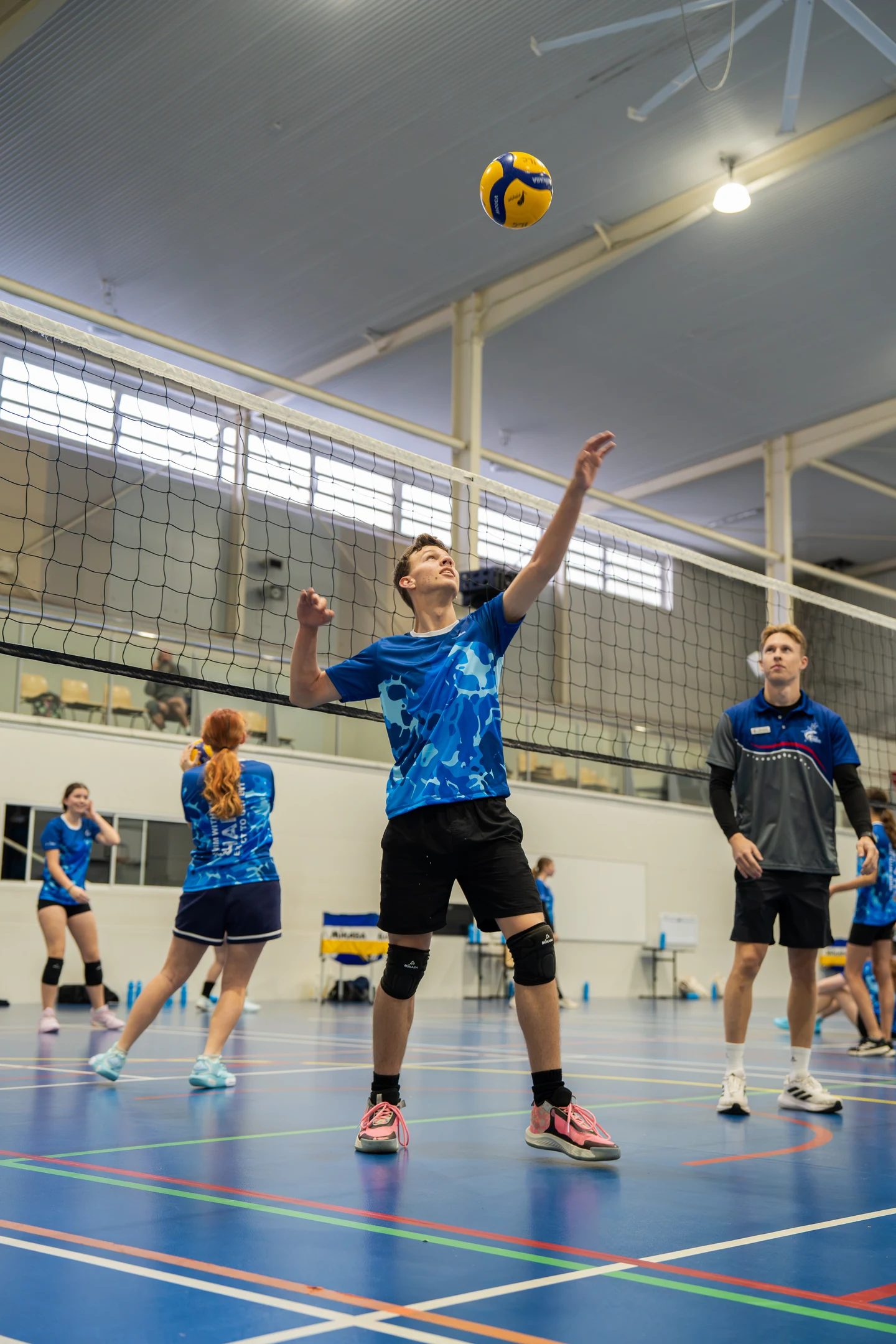 Sharks Volleyball athlete practising a serve while a coach observes