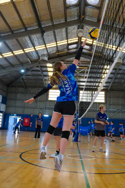 Sharks Volleyball athlete reaching to play the ball at the net during a junior session
