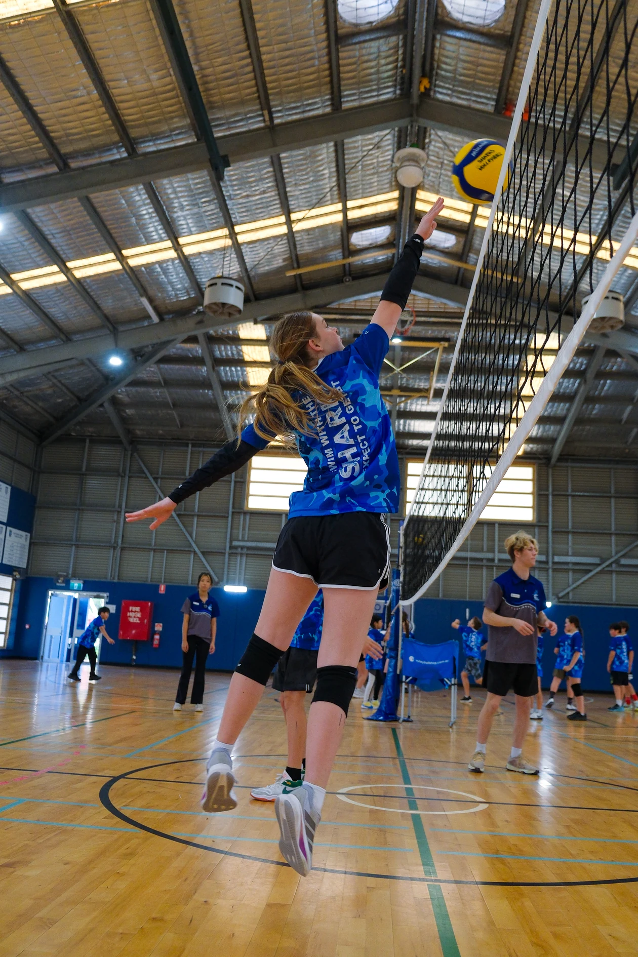 Sharks Volleyball athlete reaching to play the ball at the net during a junior session