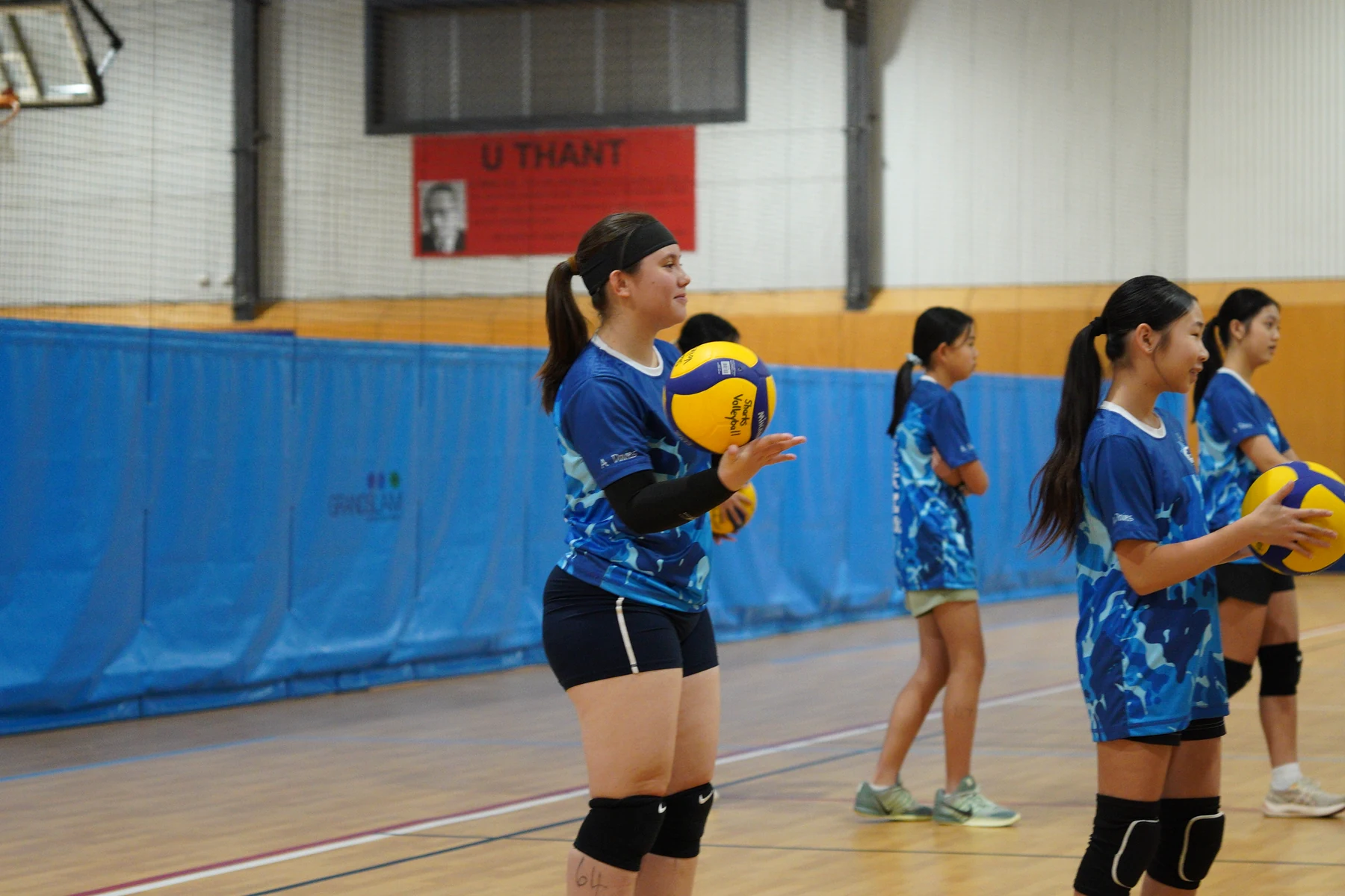 Junior Sharks Volleyball athletes holding volleyballs during a court drill
