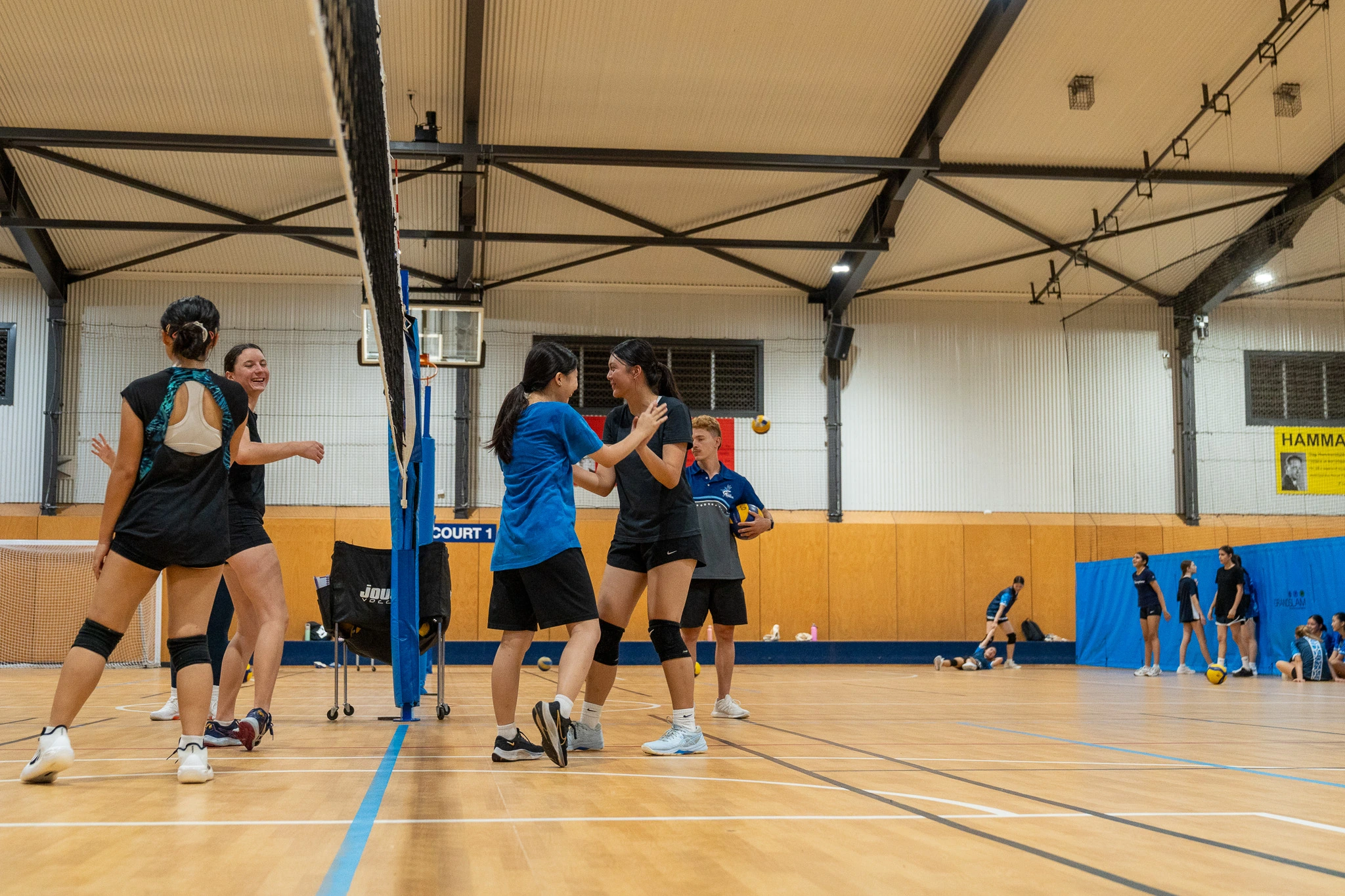 Older athletes laughing and connecting at the net with a current-uniform Sharks coach in 2026
